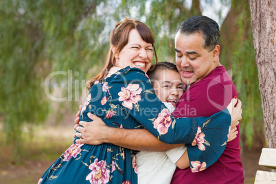 Mixed Race Young Family Hugging At The Park