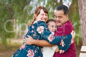 Mixed Race Young Family Hugging At The Park