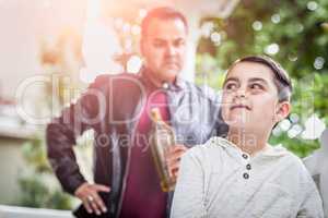 Afraid and Bruised Mixed Race Boy In Front of Angry Man Holding