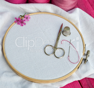 wooden round hoop with white fabric for embroidery and scissors