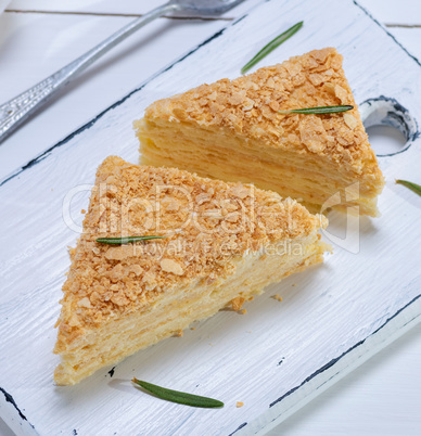 baked cakes Napoleon with cream on a white wooden board