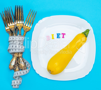 yellow squash on a white ceramic plate, next to a pile of iron f