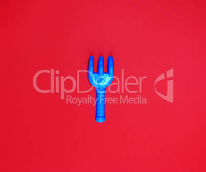 blue plastic baby rake on a red background