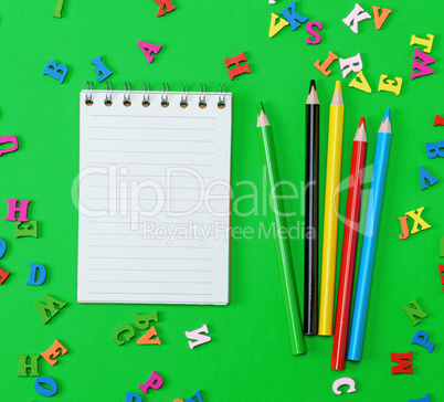 open notebook with blank white sheets in line, colored wooden pe