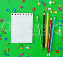 open notebook with blank white sheets in line, colored wooden pe