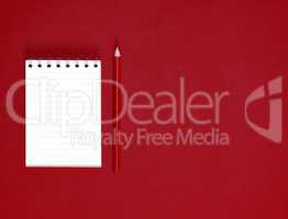 notebook with empty white sheets in line and red wooden pencil