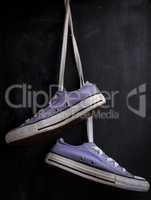 purple textile sneakers hanging on a lace