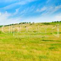 Landscape with hilly field and blue sky.
