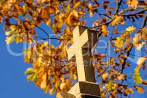 cross of a pilgrim way with autumnal painted leaves