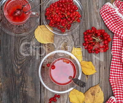 Transparent cup with hot tea from viburnum berries and fresh ber