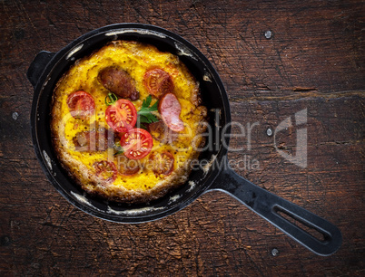 fried whipped chicken eggs with sausage pieces in a black round