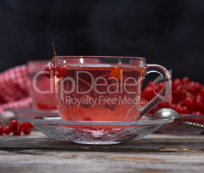 hot viburnum tea in a transparent cup with a handle and saucer