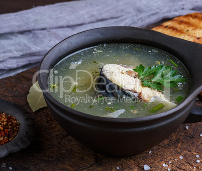 fish soup of mackerel in a brown clay plate on a wooden board