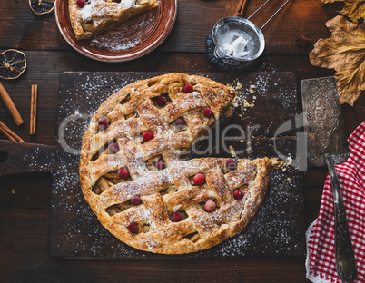 baked whole round apple pie on a rectangular old brown cutting b