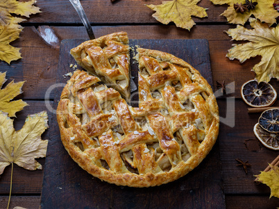 baked whole round apple pie on a rectangular old brown cutting b