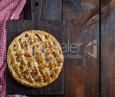 Baked whole round apple pie on a rectangular old brown board