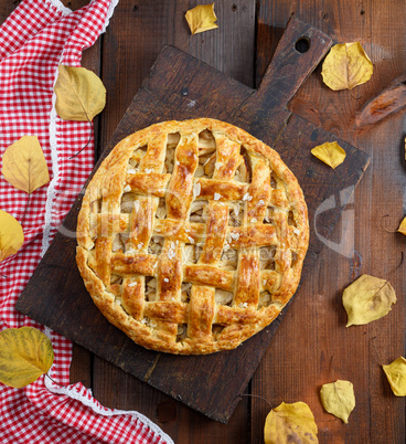 baked whole round apple pie on a brown wooden board