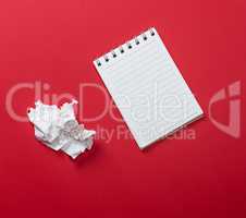 notebook with white sheets and a crumpled ripped out sheet of pa