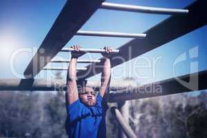 Determined boy exercising on monkey bar during obstacle course