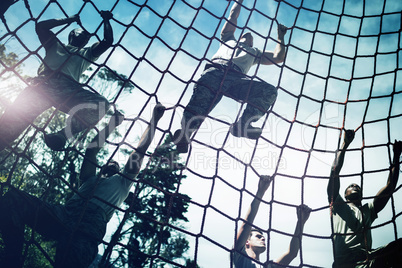 Military soldiers climbing rope during obstacle course