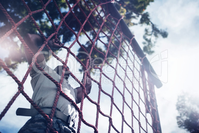 Military soldier climbing rope during obstacle course