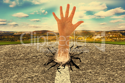 Outstretched hand sticks out of the street