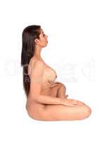 Woman sitting nude on the floor in yoga pose