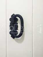 Door handle in black metal, on white door.