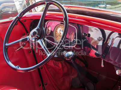 Red interior with classic car dashboard and steering wheel.