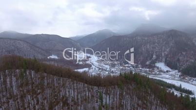 Aerial video of snow falling on small village in the mountains