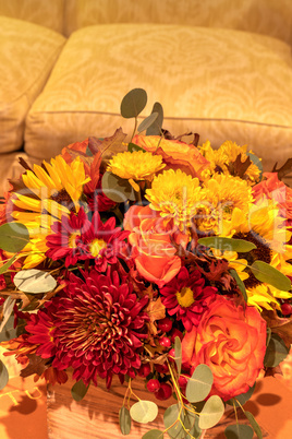 Fall colored flower bouquet that includes orange roses, yellow s
