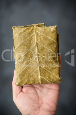 Raw tempeh wrapped in leaf on hand.