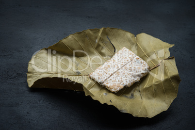 tempeh wrapped in leaf, dark background.