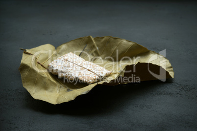 Fresh tempeh wrapped in leaf, dark background.
