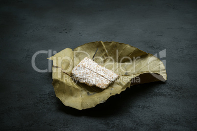 Raw tempeh wrapped in leaf, dark background.