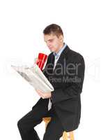 Man sitting in suit drinking and reading paper