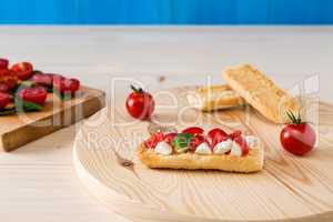 Italian crostini with mozzarella, cherry tomatoes and basil on a