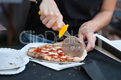 Pizza maker cutting a pizza margherita