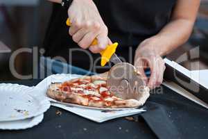 Pizza maker cutting a pizza margherita