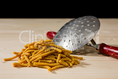 Passatelli original Italian pasta over a wooden background