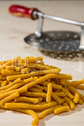 Closeup of Passatelli original Italian pasta over a wooden backg