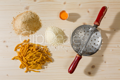 Passatelli original Italian pasta and ingredients over a wooden