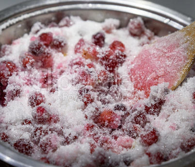 berries of ripe red cranberries with sugar in an iron pan