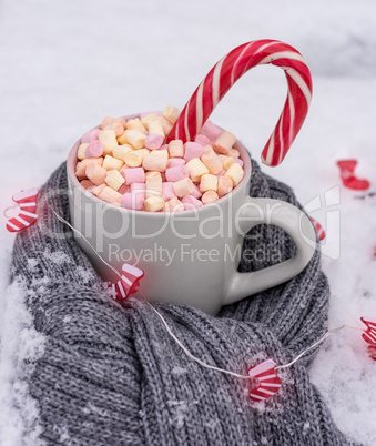 ceramic cup with hot chocolate with marshmallows on white snow w