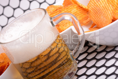 Glass of light beer and potato chips on a abstract background