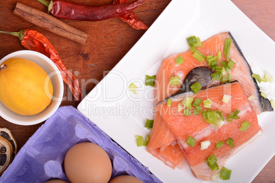 fresh salmon fillet on white plate. red pepper, cinnamon and lemon