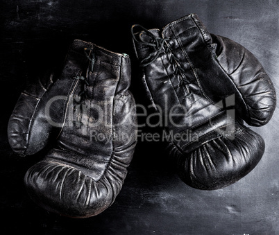 pair of old leather boxing gloves with laces on a wooden backgro