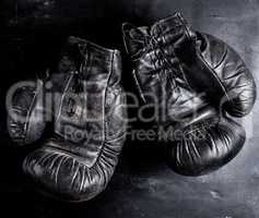 pair of old leather boxing gloves with laces on a wooden backgro