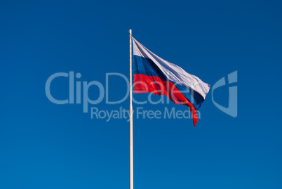 The Russian flag on the flagpole fluttering in the wind on blue sky background. Tula, Russia
