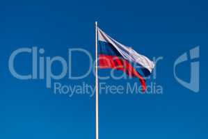 The Russian flag on the flagpole fluttering in the wind on blue sky background. Tula, Russia